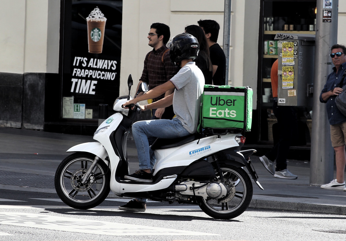 Archivo - Un repartidor de la empresa de comida a domicilio, Uber Eats, circula con su moto por una calle de Madrid.