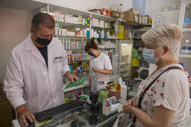 Archivo - Una mujer adquiere las mascarillas gratuitas que el Gobierno andaluz empieza desde este miércoles 22, a través de las farmacias, a los ciudadanos mayores de 80 años. La medida beneficiará a todos los mayores de 65 años y a los menores de esa eda