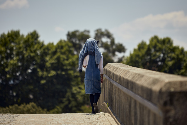 Archivo - Una persona se protege del sol en un puente de la ciudad de Ourense