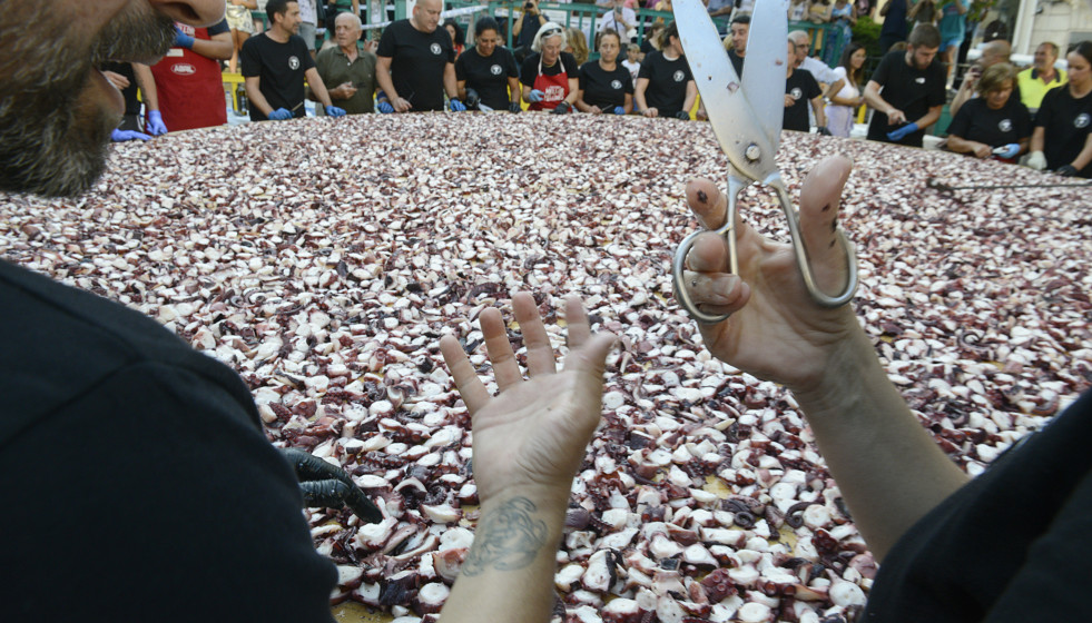 Archivo - Una persona sostiene unas tijeras frente a kilos de pulpo troceado en O Carballiño.
