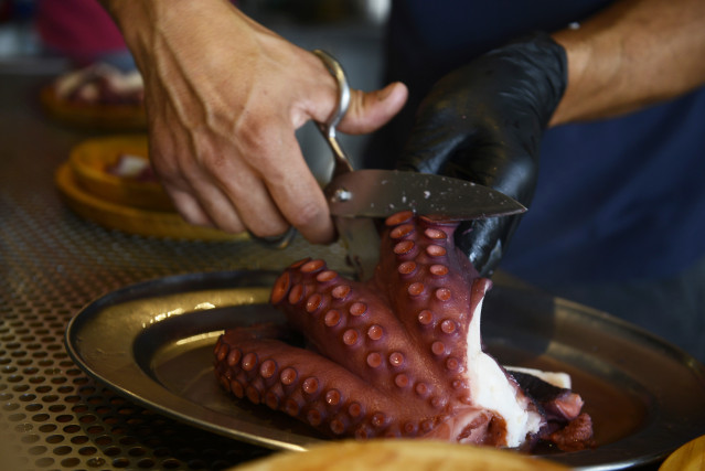 Archivo - Una persona corta un pulpo con tijeras, durante la celebración de la Fiesta del Pulpo, a 8 de agosto de 2021, en O Carballiño, Ourense