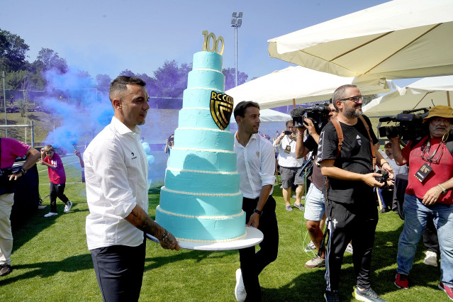 Iago Aspas y Kevin Vázquez llevan una gran tarta de cumpleaños, en el acto institucional de celebración del centenario del Real Club Celta, celebrado el 23 de agosto de 2023 en la ciudad deportiva Afouteza de Mos (Pontevedra).