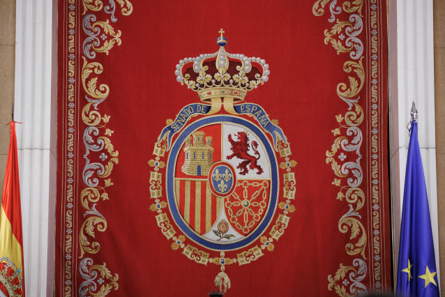 Escudo en el hemiciclo del Senado que se basa en las normas existentes sobre el Escudo de España, en el que se inspiran los cuarteles, y en el Escudo de armas de la monarquía española, en el que se inspiran la forma y los adornos, a 17 de agosto de 2023,