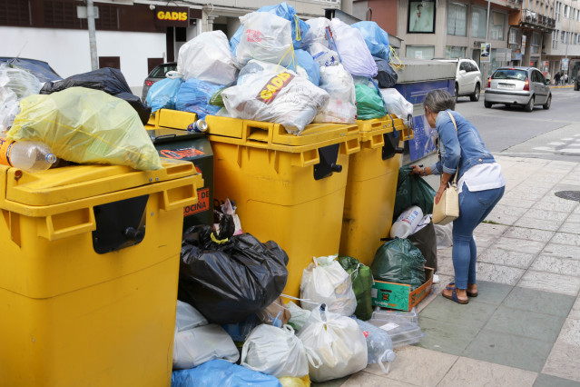 Una mujer deposita una bolsa de basura al lado de contenedores de basura desbordados durante la cuarta semana de la huelga en la recogida de basura de Vilalba, a 11 de septiembre de 2023, en Vilalba, Lugo, Galicia (España). Hoy se cumplen 22 días desde qu