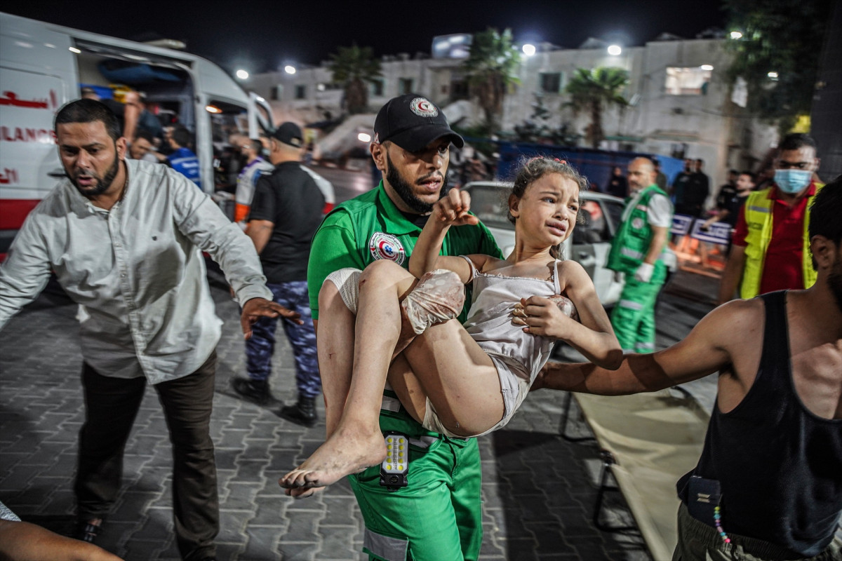 Un paramédico sostiene a una niña que llora después de ser sacada del lugar del bombardeo el 9 de octubre de 2023 en Gaza, Palestina en una foto de Saher Alghorra