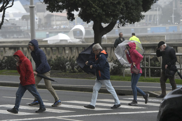 Varias personas se protegen de la lluvia y el viento con paraguas, a 20 de octubre de 2023, en A Coruña
