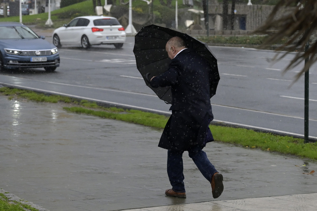 Un hombre con paraguas trata de refugiarse del viento y de la lluvia, a 4 de noviembre de 2023, en A Coruña, Galicia (España). La Agencia Estatal de Meteorología (AEMET) ha activado en A Coruña el