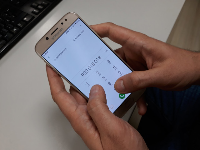 Archivo - Una persona llama al teléfono del acoso escolar