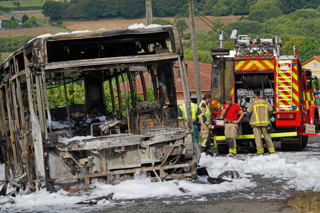 Archivo - El autobús calcinado junto a varios bomberos durante el dispositivo de extinción del incendio, donde ha fallecido un bombero en prácticas, a 30 de agosto de 2022, en A Cacharela, de la parroquia de Aríns, Santiago de Compostela, A Coruña, Galici