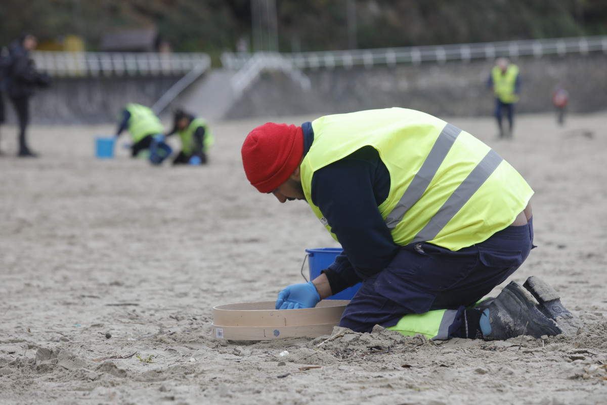 Operarios de TRAGSA recogen pellets de plástico, en la playa de Aguilar, a 9 de enero de 2024, en Muros de Nalón, Asturias (España). El Principado de Asturias ha activado el nivel dos de emergencia