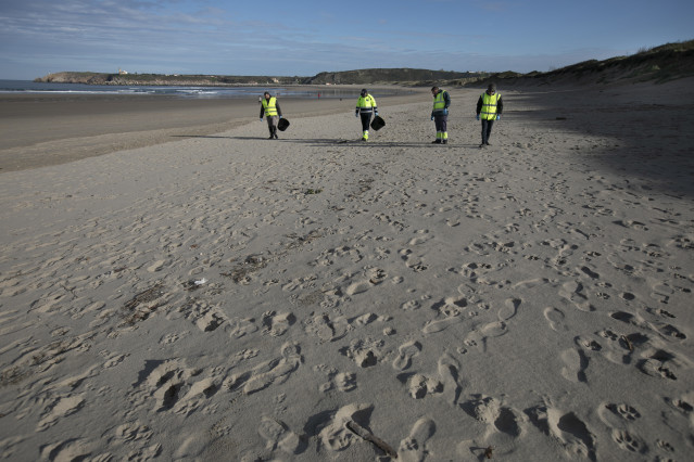 Archivo - Varios hombres recogen pellets en la playa de Salinas, a 13 de enero de 2024, en Castrillón, Asturias (España). La conocida ya como la ‘marea blanca’ se prevé que proceda de los seis contenedores del buque Toconao que cayeron al mar en aguas por