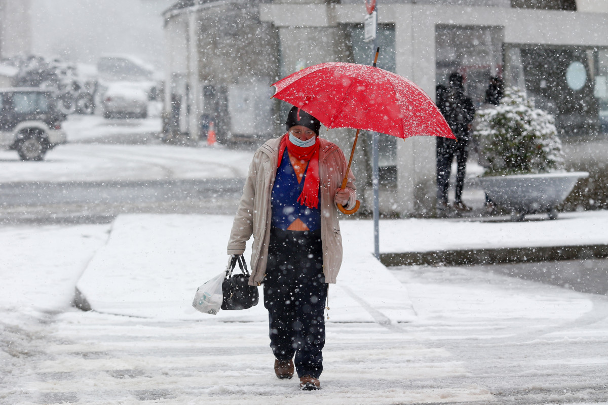 Archivo - Un hombre se refugia de la nieve con un paraguas en una calle de Pedrafita do Cebreiro, a 5 de enero de 2024, en Pedrafita do Cebreiro, Lugo