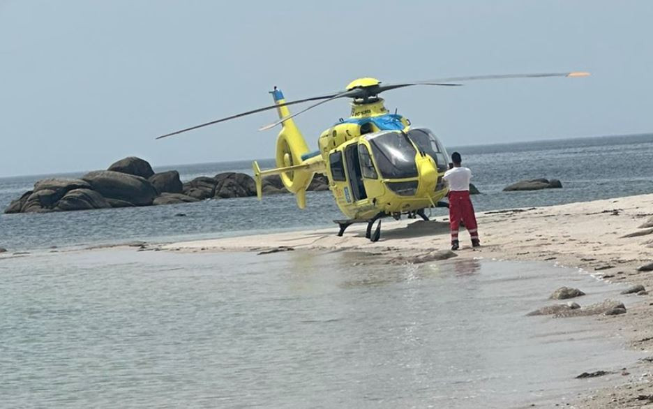 El helicóptero del 061 en la playa de Carnota tras intentar rescatar al ahogado en una foto de @HelicoSantiago
