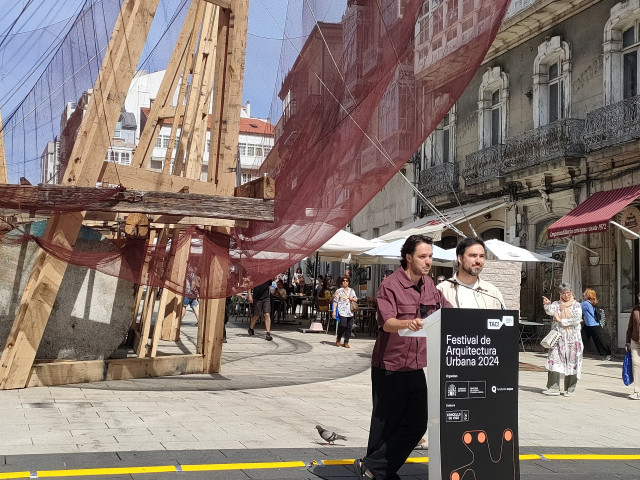 Los arquitectos Óscar Cruz y Pablo Paradinas, ganadores del festival TAC! de arquirectura urbana, ante la instalación ¡Qué faena(r)!, que simula una gran batea cubierta por una red de pesca, en la Porta do Sol de Vigo.