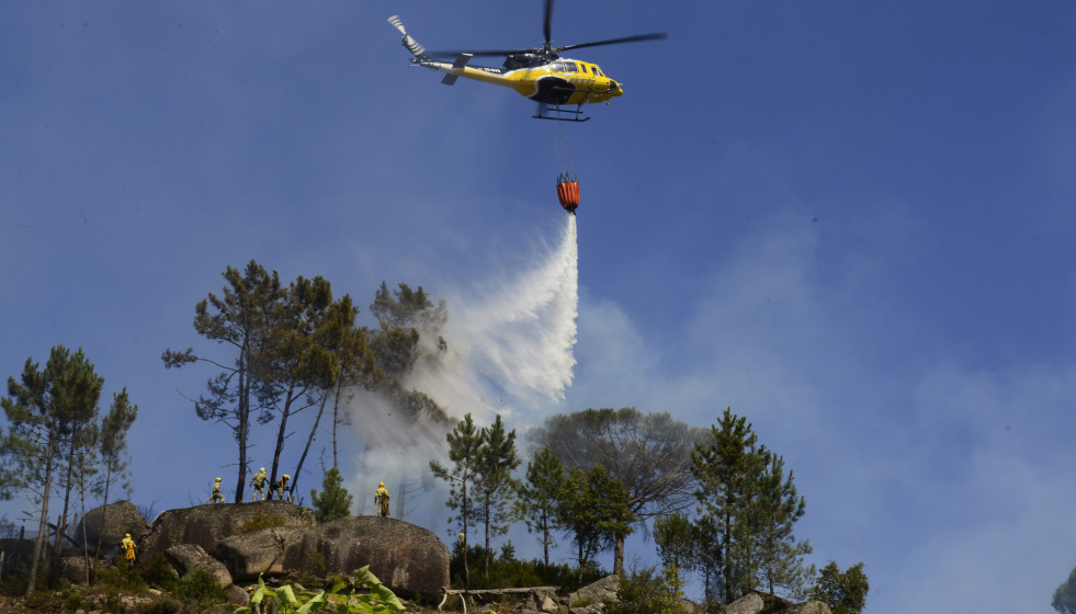Archivo - Un helicóptero arroja agua sobre un incendio forestal, a 28 de julio de 2021, en la parroquia de Santa Mariña do Monte, Ourense, Galicia (España). Un total de seis aviones y dos helicópt