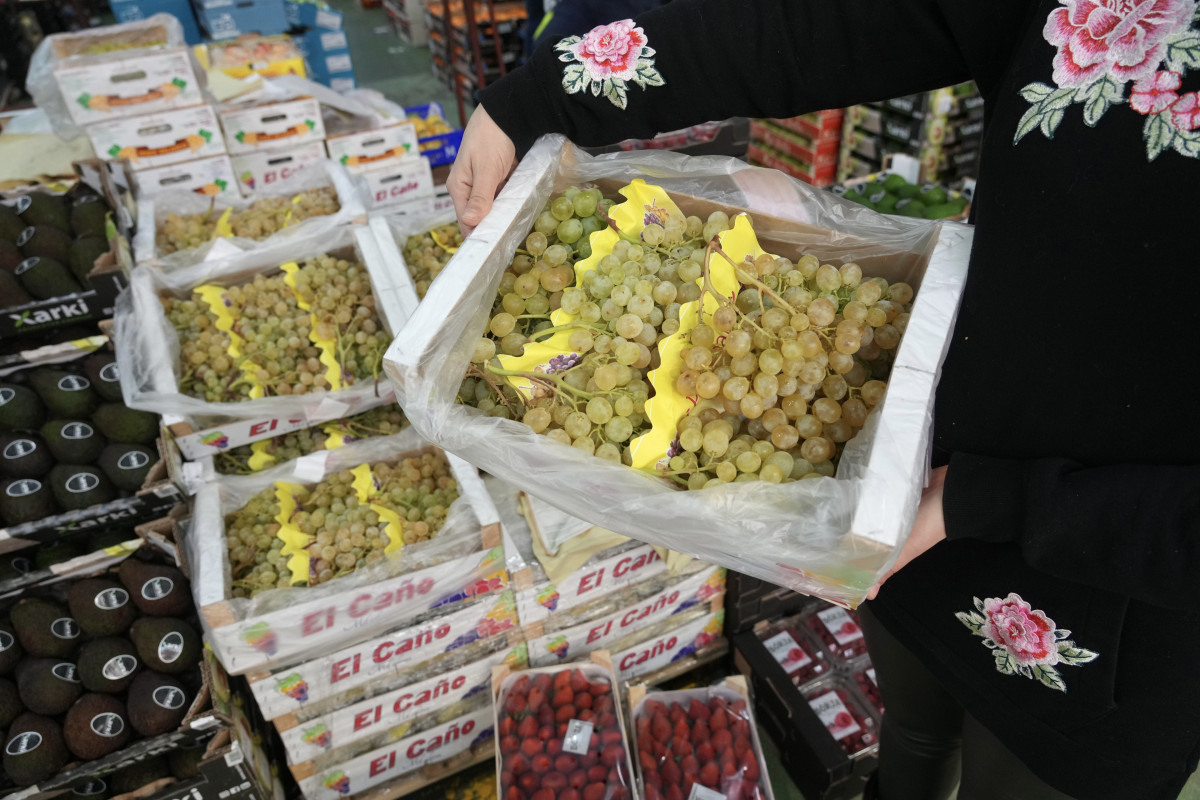 Archivo - Una persona sujeta una caja de uvas