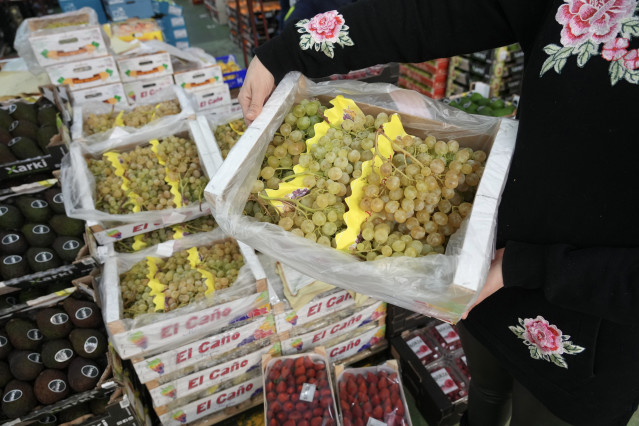 Archivo - Una persona sujeta una caja de uvas