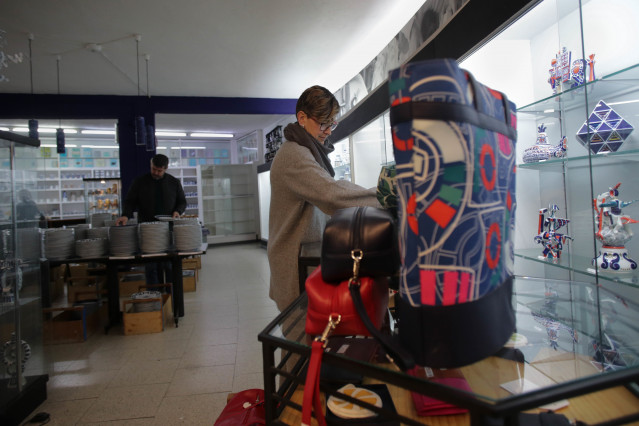 Archivo - Una mujer revisa unos complementos a la venta durante la primera jornada de estas rebajas, en el entorno de la Planta Circular de Sargadelos.