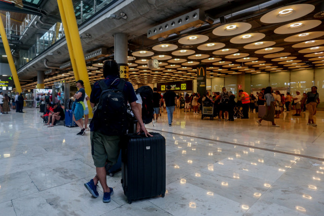 Archivo - Varias personas junto a sus maletas con motivo de la operación salida del puente de agosto, en la T4, en el aeropuerto Adolfo Suárez Madrid-Barajas, a 14 de agosto de 2024, en Madrid (España). Los aeropuertos de la red de Aena en España tienen p