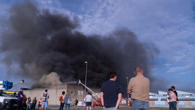 Varias personas observan el incendio de una nave en Sada (A Coruña).
