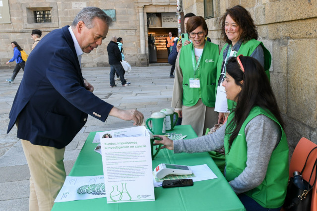 El conselleiro de Sanidade, Antonio Gómez Caamaño, en la mesa de la Asociación Contra el Cáncer (AECC), en la Plaza del Obradoiro, en Santiago de Compostela