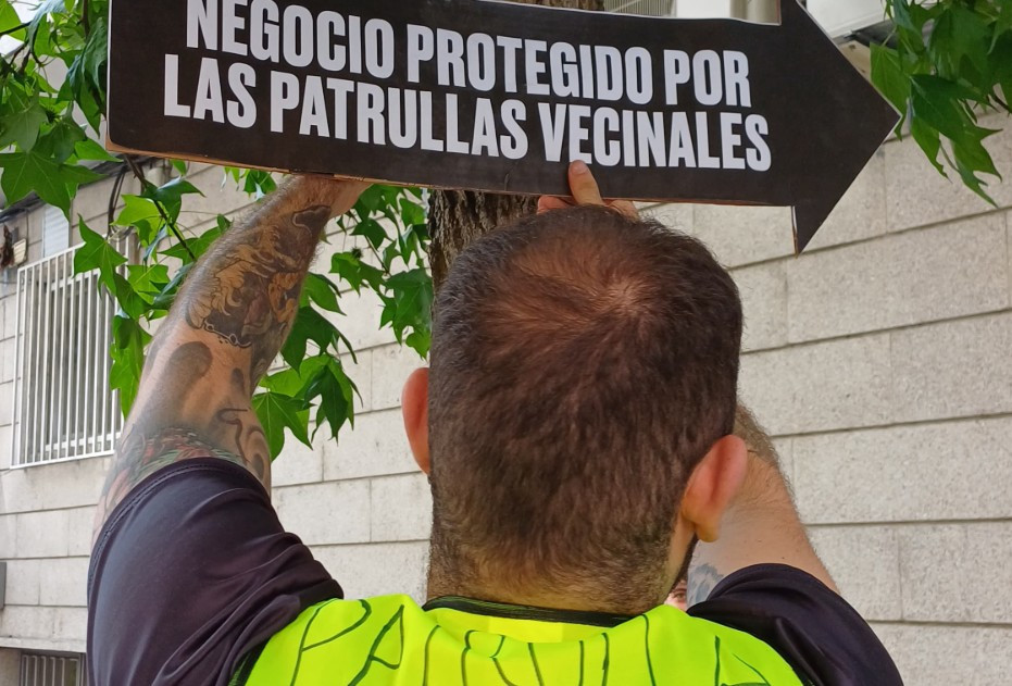 Vigilante colocando cartel a un negocio del barrio de A Ponte en una foto del X de Roberto Vaquero