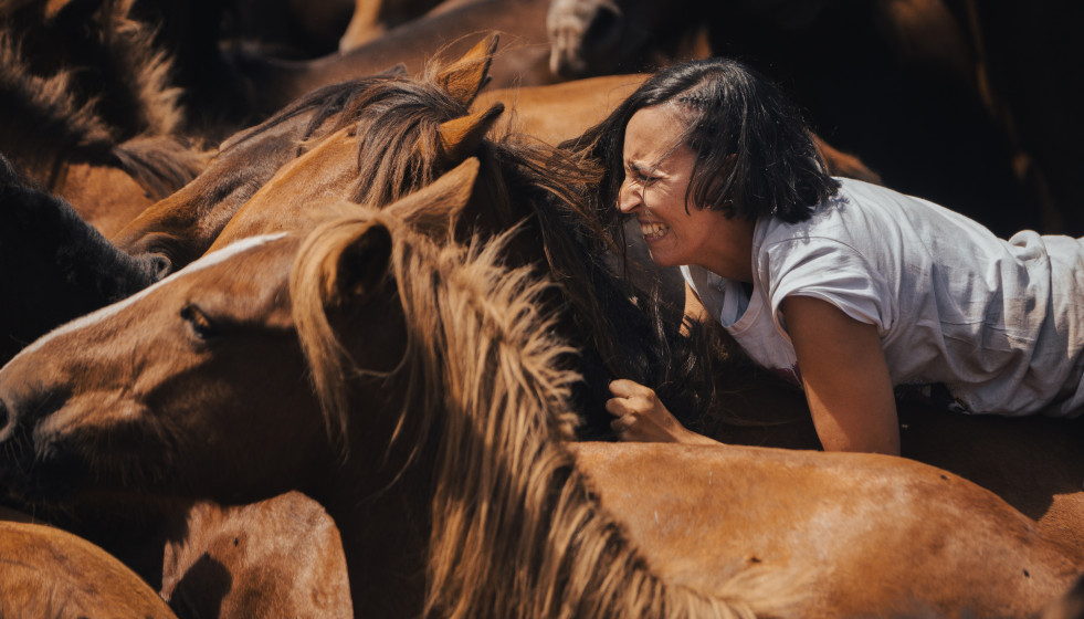 Archivo - Una mujer sujeta a un caballo salvaje durante el segundo curro de la Rapa das Bestas 2024, a 7 de julio de 2024, en Sabucedo, Pontevedra, Galicia.