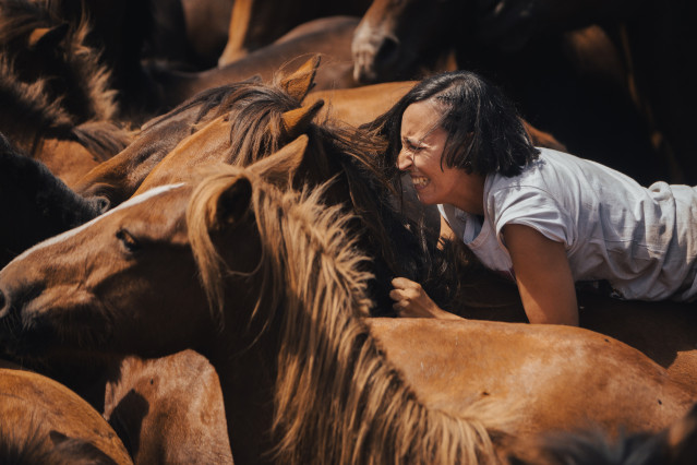 Archivo - Una mujer sujeta a un caballo salvaje durante el segundo curro de la Rapa das Bestas 2024, a 7 de julio de 2024, en Sabucedo, Pontevedra, Galicia.