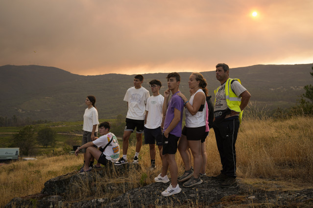 Varias personas observan las labores de extinción, a 30 de julio de 2025, en A Cañiza.