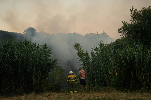 Dos personas observan el fuego, a 29 de julio de 2025, en Arbo, Pontevedra, Galicia.