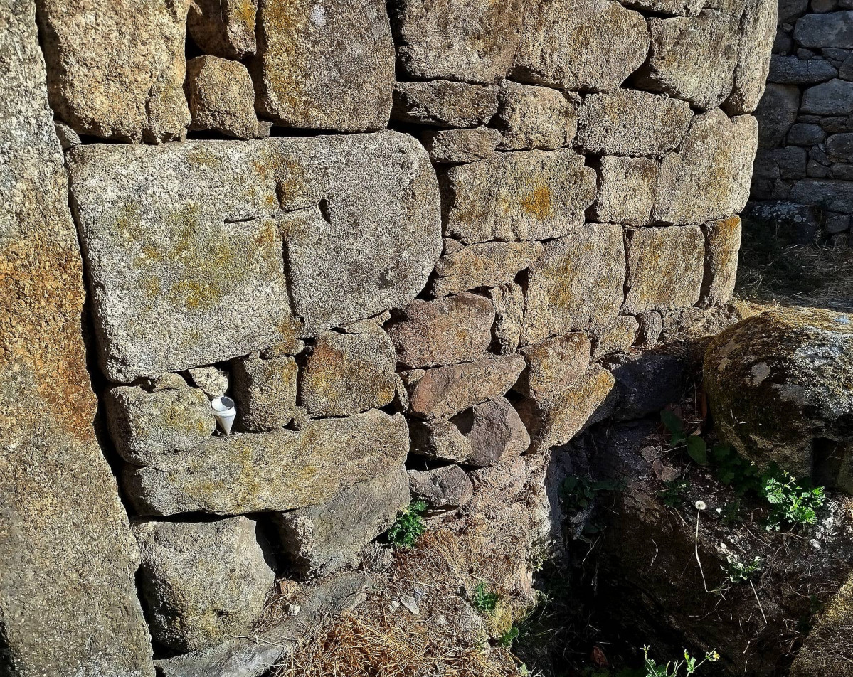 Cruz latina de brazos potenzados gravada nun sillar da palleira na que estu00e1 o sillar coa inscripciu00f3n probablemente medieval da Madanela