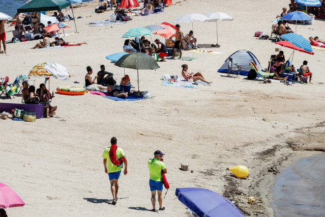 Archivo - Imagen de una playa en verano, con dos socorristas caminando por la arena.