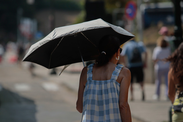 Una mujer se protege del sol con una sombrilla.