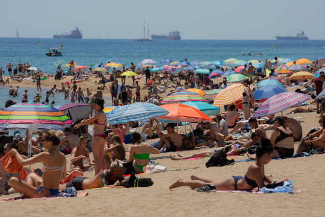 Archivo - Varias personas se protegen del sol en la playa de la Barceloneta, a 13 de julio de 2022, en Barcelona, Catalunya (España). La intensa y extensa ola de calor llega hoy a su momento cumbre, aunque ese pico se mantendrá durante varios días seguido