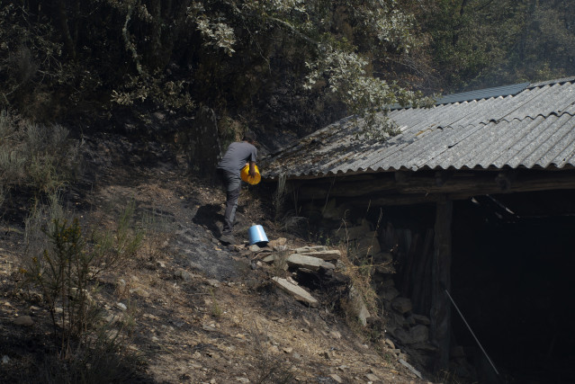 Ganadero propietario de algo más de cien vacas en Teixeira, intenta sofocar el fuego en uno de los refugios de los animales, a 10 de agosto de 2025, en Maceda, Ourense, Galicia (España).