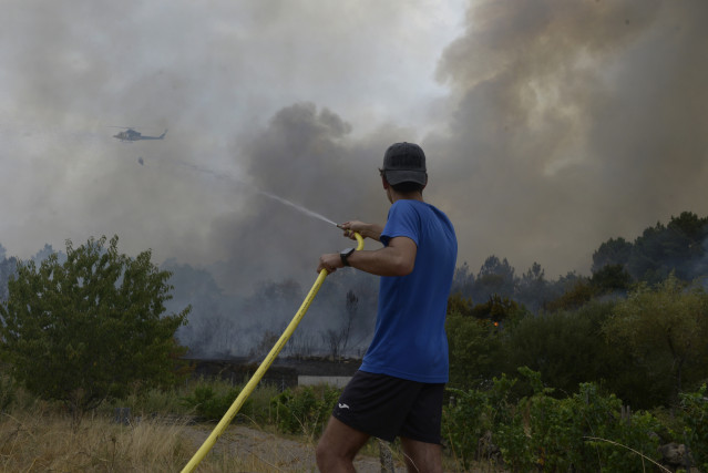 Extinción del incendio declarado a partir de la vía del tren en Seixalbo, en un terreno en el que ardieron varias colmenas