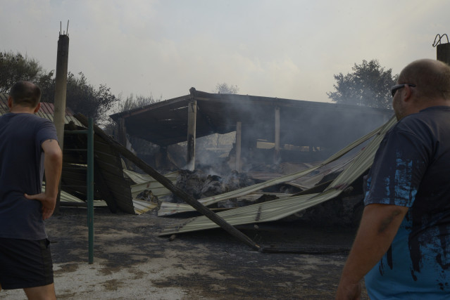 Dos ganaderos observan el estado de su granja tras el paso del fuego, a 13 de agosto de 2025, en Cova, Pobra de Trives, Ourense, Galicia (España).