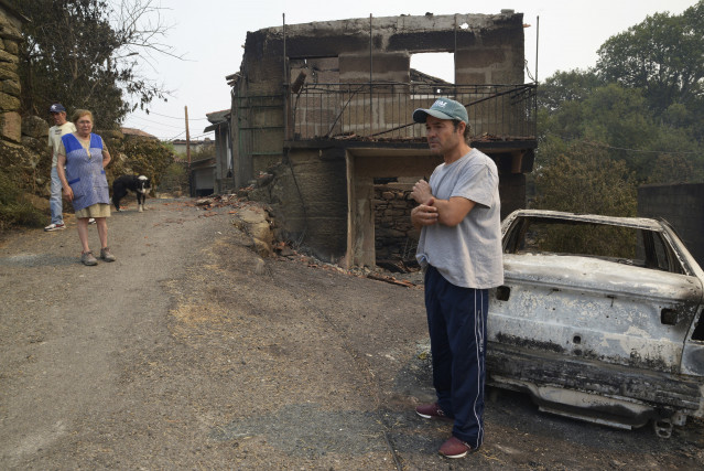 Samuel, vecino de A Caridade (Cualedro) delante de su casa destruída por el fuego, igual que propiedades de sus vecinos Dosinda y José Antonio