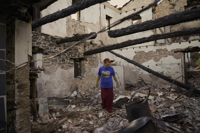 Una mujer observa su casa destruida por el incendio, a 20 de agosto de 2025, en San Vicente de Arriba, Ourense, Galicia (España).