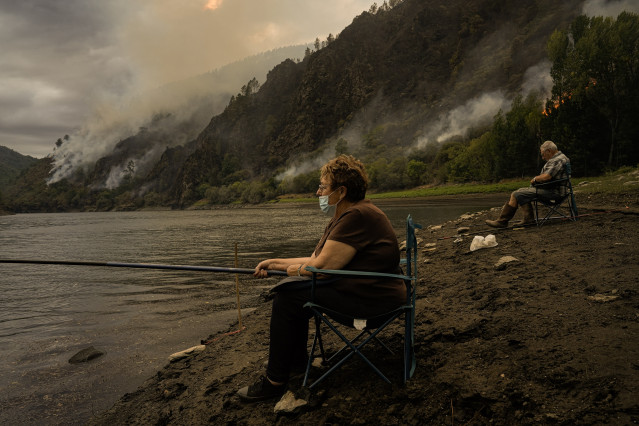 Una pareja pesca cerca el fuego.