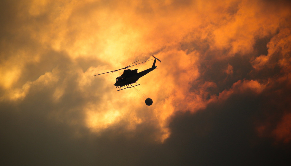 Un helicóptero recoge agua para ayudar con las labores de extinción del incendio, a 26 de agosto de 2025, en Aguas Mestas, Lugo, Galicia (España).