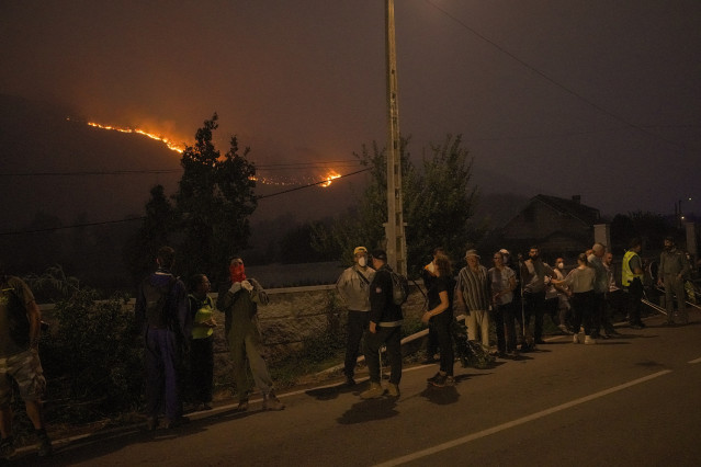 Varias personas observan un fuego, a 17 de agosto de 2025, en Retorta, Laza, Ourense, Galicia (España).