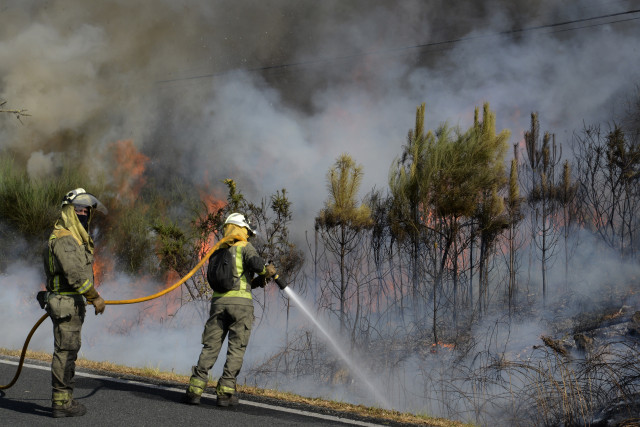 Archivo - Varios bomberos intentando apagar un fuego en la provincia de Ourense, Galicia