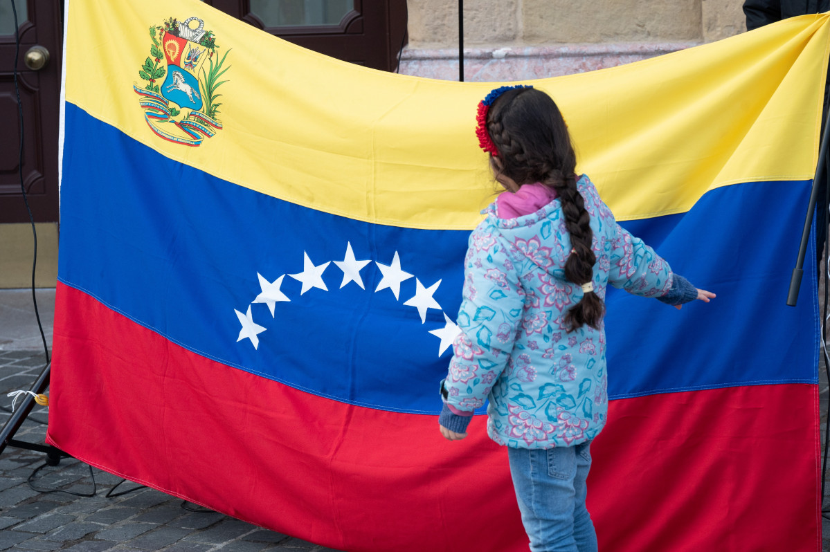 Archivo - Una niña frente a la bandera venezolana durante una concentración ‘Por una Venezuela libre’