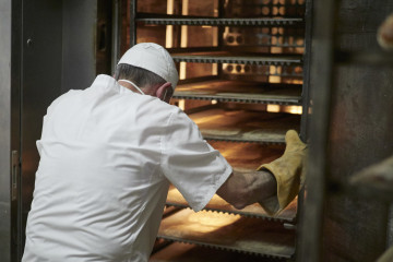Archivo - Un trabajador protegido con mascarilla y guantes maneja bandejas para cocer el pan en el obrador panadería 'Panadero de Eugui' durante en el día 32 del estado de alarma, uno de los estable