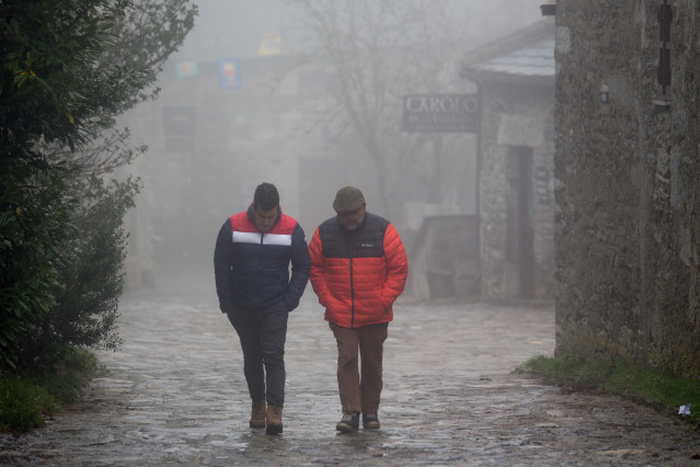 Archivo - Dos hombres caminan entre la niebla en la aldea prerromana de O Cebreiro, Concello de Pedrafita do Cebreiro, Lugo, Galicia.