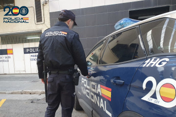 Un agente de la Policía Nacional frente a un coche patrulla.