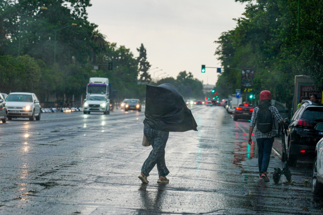 Archivo - Viandantes con paraguas por la zona del Parque de María Luisa, a 18 de mayo de 2023, en Sevilla, (Andalucía, España).