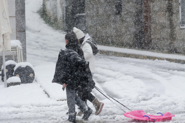 Archivo - Dos personas caminan con un trineo por la nieve, a 18 de enero de 2023, en Castroverde, Lugo, Galicia (España).