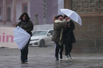 Varias personas intentan sujetar sus paraguas, a 26 de enero de 2026, en Santiago de Compostela, A Coruña, Galicia (España).